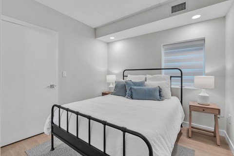 A bedroom with a black metal bed frame and a white bedspread.