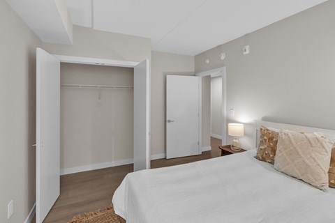 A bedroom with a bed, a lamp, and a closet.