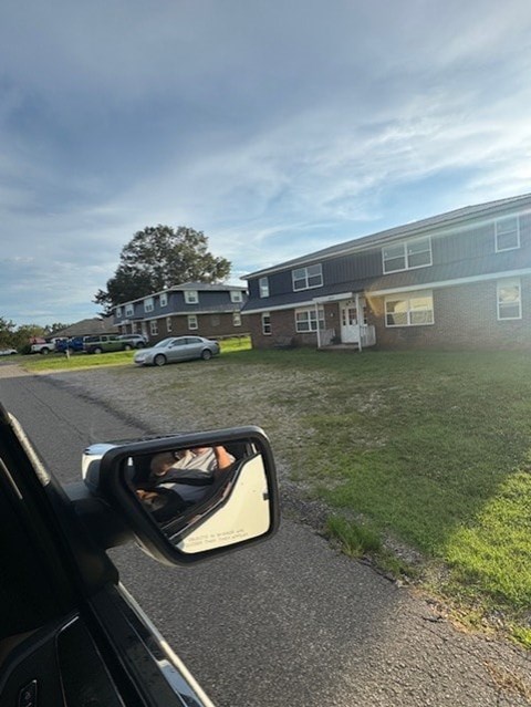 A car is parked in front of a building with a grassy area in the foreground.