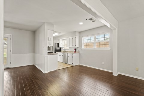 A spacious kitchen with white cabinets and a window.