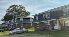 A car is parked in front of a two-story house.
