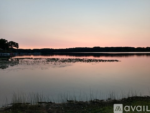 A calm lake with a reflection of the sky and some trees in the distance.