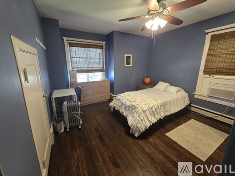 A bedroom with a white bed and a ceiling fan.