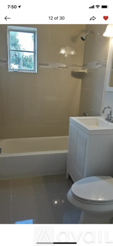 A white toilet in a bathroom with a window above it.