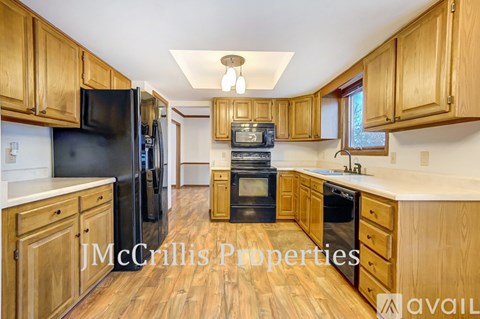 A kitchen with wooden cabinets and black appliances is available for rent.
