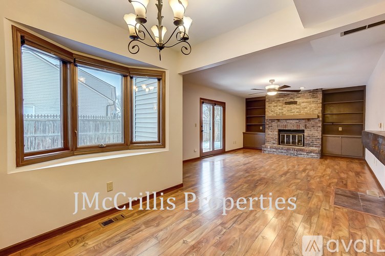 A spacious living room with wood flooring and a stone fireplace is available for rent.