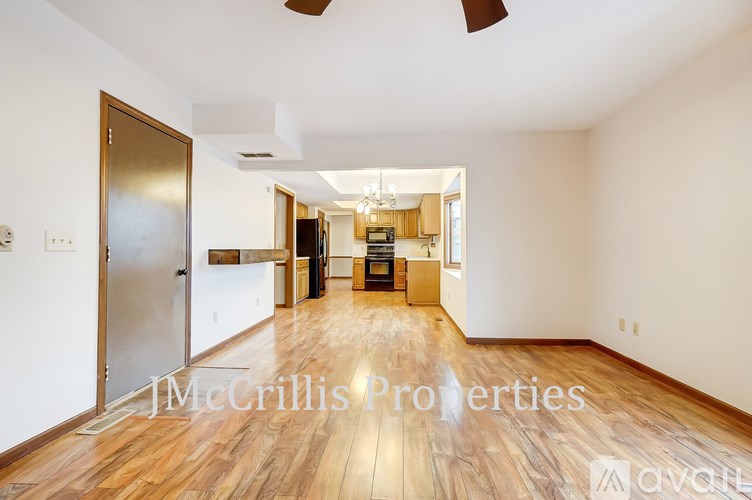 A spacious room with wooden floors and a ceiling fan.