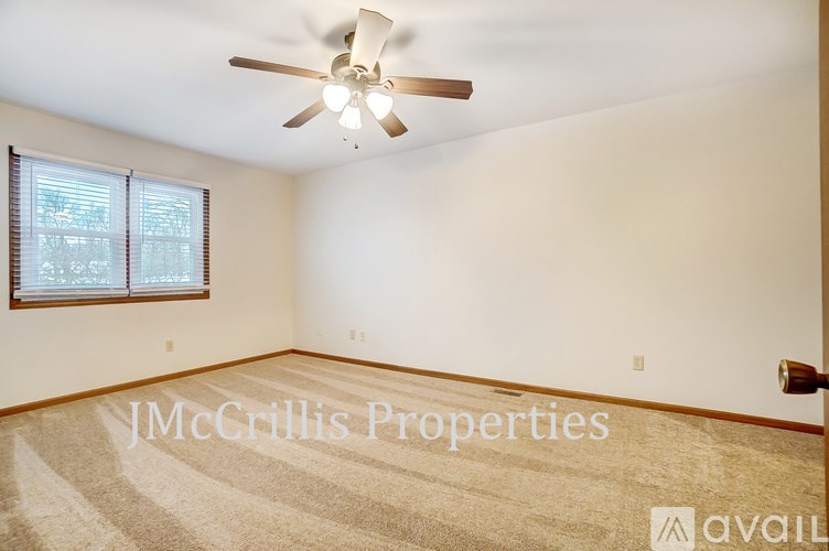 A room with a ceiling fan and a window with blinds.