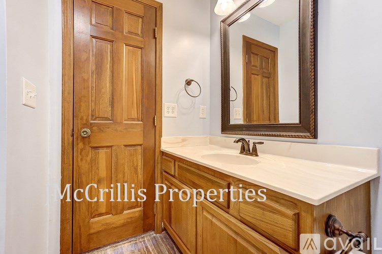 A bathroom with a wooden door and a mirror above a sink.