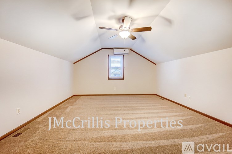 A room with a carpeted floor and a ceiling fan.