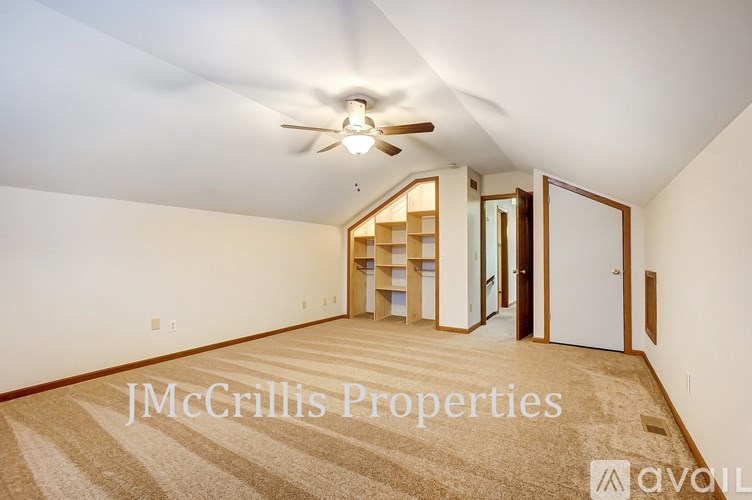 A room with a carpet floor and a ceiling fan.
