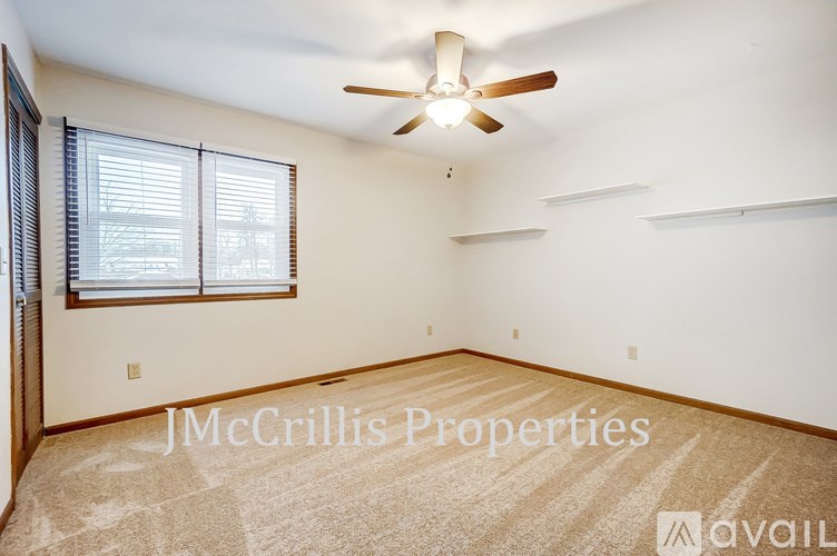 A room with a ceiling fan and a window with blinds.