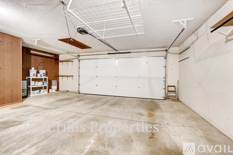 A large, empty garage with a white door and a brown cabinet on the left side.