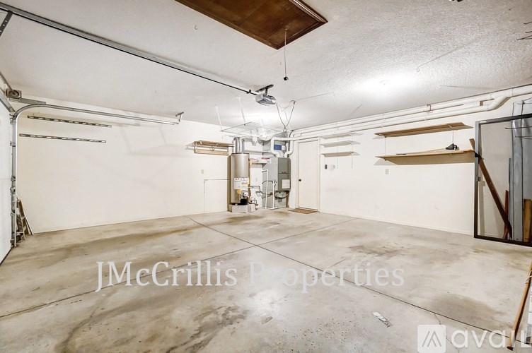 A large, empty room with a concrete floor and white walls, with a door in the background and a wooden beam on the ceiling.