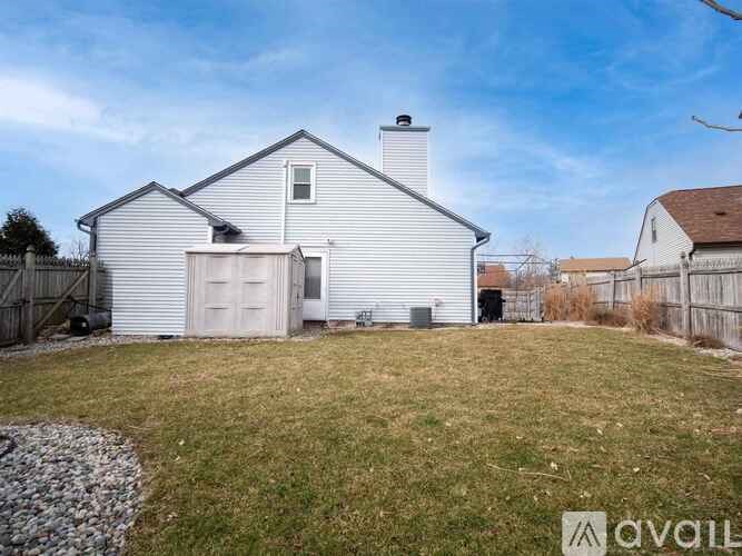 A house with a white exterior and a chimney is surrounded by a fence and has a grassy yard.