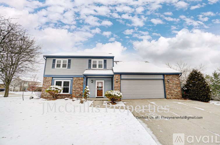 A house with a snowy front yard and a blue sky with clouds.