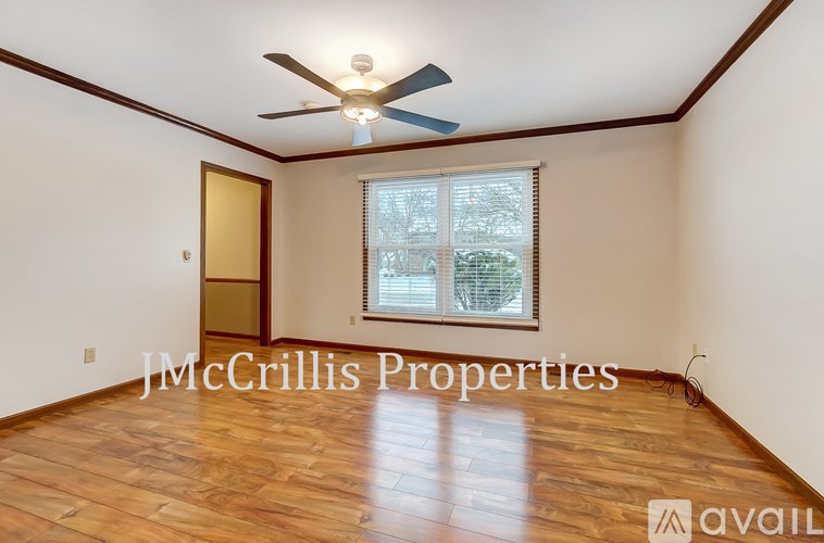 A room with wooden flooring and a ceiling fan is available for rent.