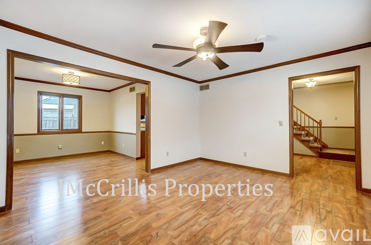 A McGrillis Properties sign is on a wall in an empty room with wood floors and a ceiling fan.