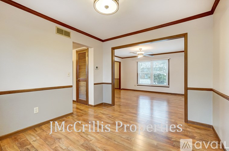 A room with wooden floors and white walls, with a window and a door visible.