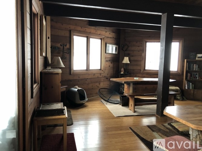 A cozy wooden cabin interior with a table, chairs, and a window.