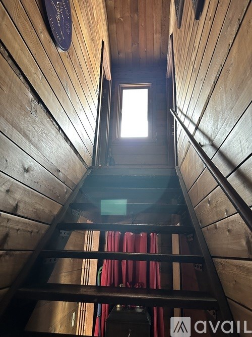 A wooden staircase with a metal railing leading to a bright light at the top.