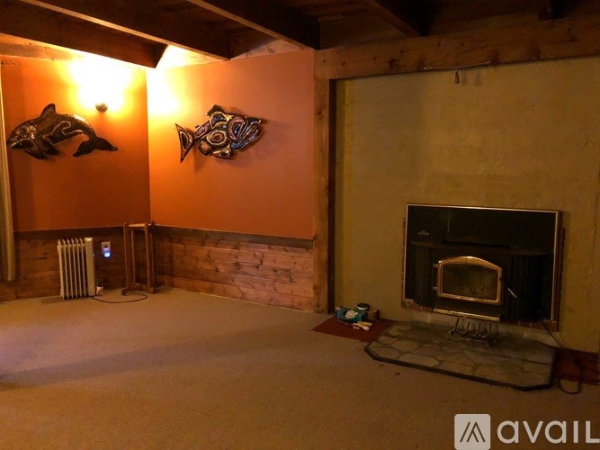 A room with a fireplace and two fish decorations on the wall.