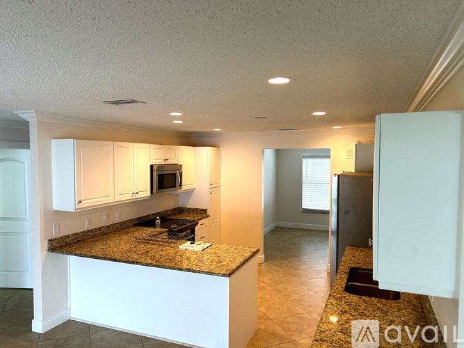 A kitchen with granite countertops and white cabinets.