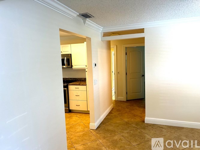 A hallway with a kitchen area visible through the doorway.