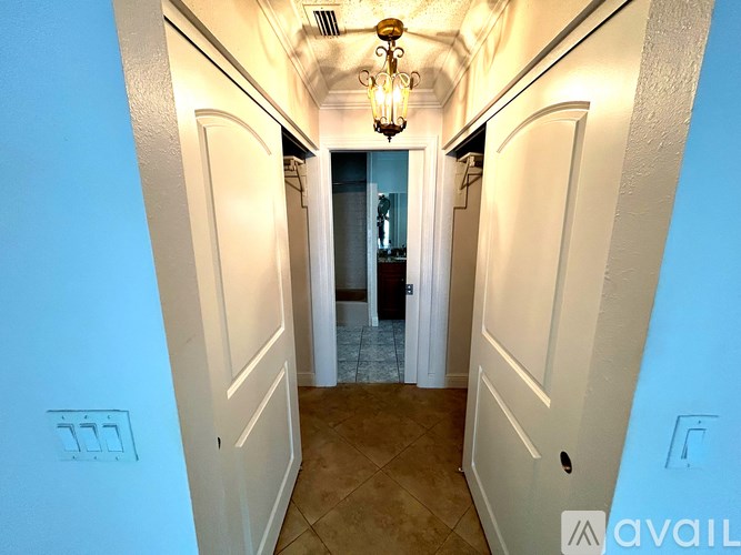 A hallway with a chandelier and white walls.