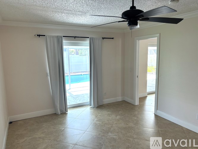 A room with a ceiling fan and sliding glass doors leading to a patio.