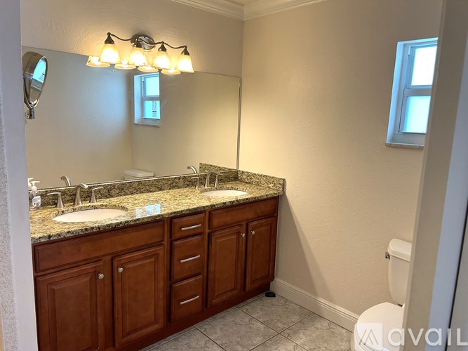 A bathroom with a granite countertop and wooden cabinets.