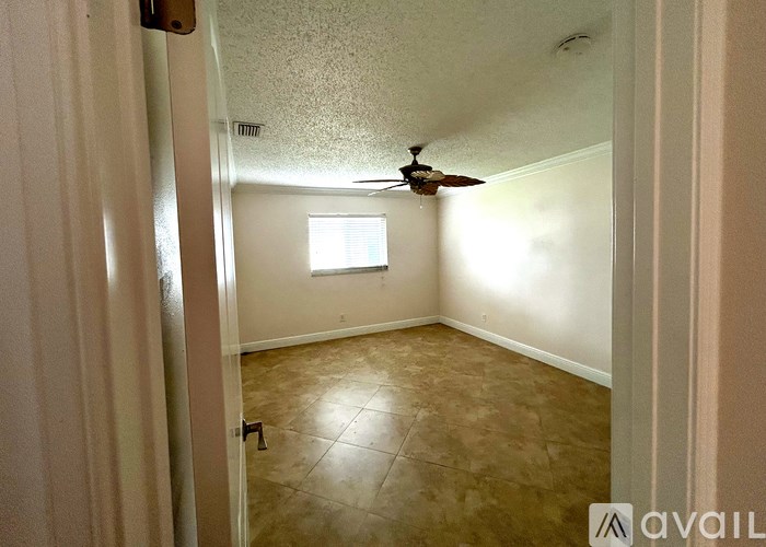 A room with a ceiling fan and a window.