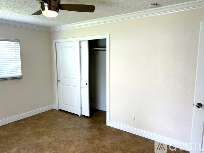 A room with a ceiling fan and a door leading to another room.