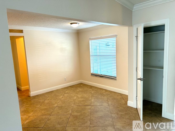 A room with a window covered by blinds and a tile floor.