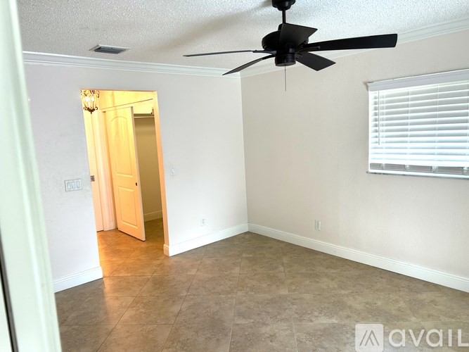 A room with a ceiling fan and a doorway leading to another room.