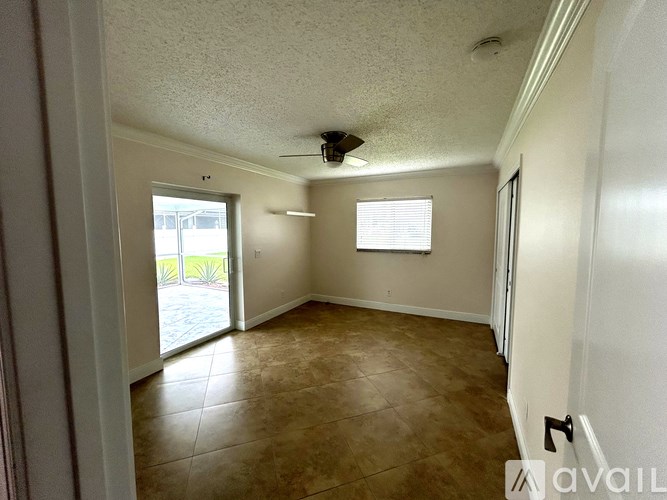 Empty room with a ceiling fan and sliding glass doors.