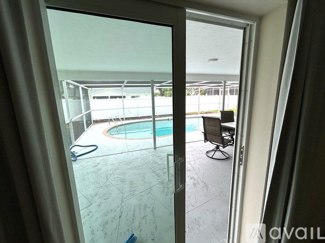 A glass door opens to a patio with a pool and a chair.