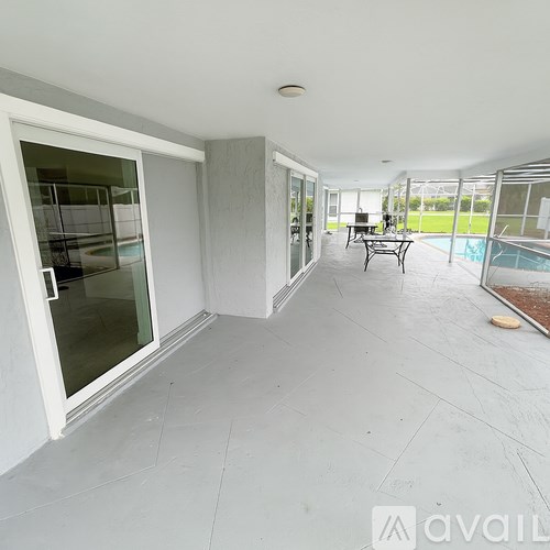 A patio area with a table and chairs and a pool in the background.
