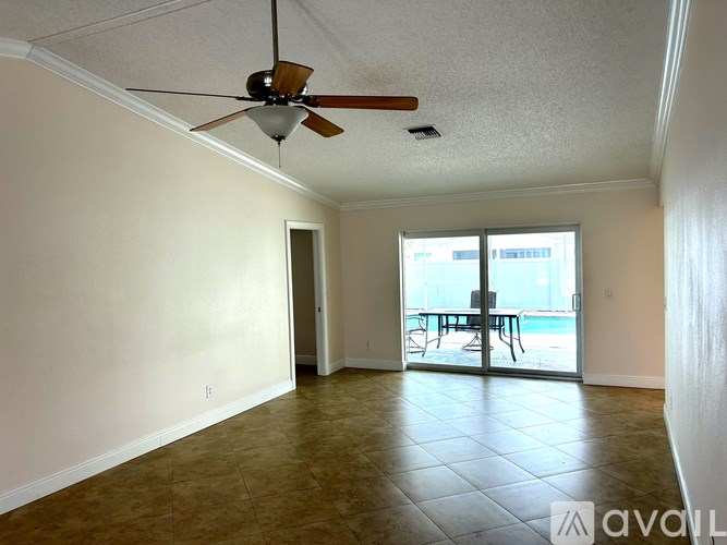 A person is sitting on a chair in a patio area with a pool.