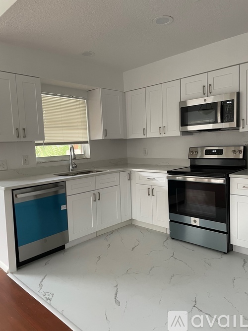 A kitchen with white cabinets and a marble floor.