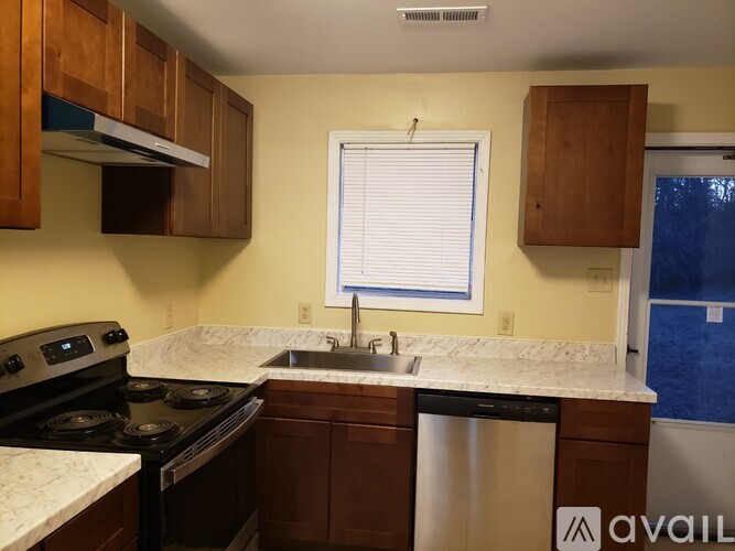 A kitchen with a stove, sink, and cabinets.
