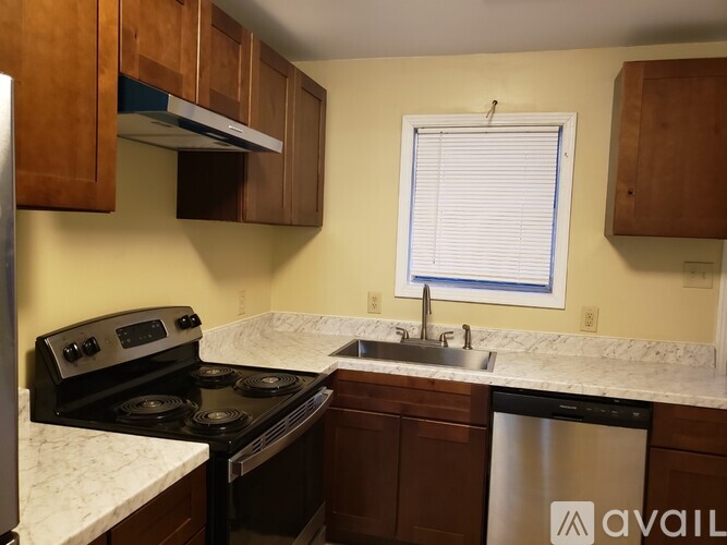 A kitchen with a stove, sink, and cabinets.
