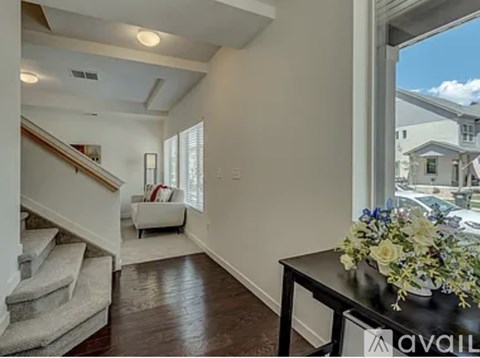 A living room with a staircase and a table with flowers on it.