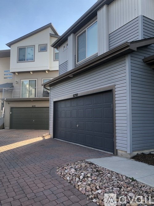 A house with a grey garage door and a driveway made of bricks.