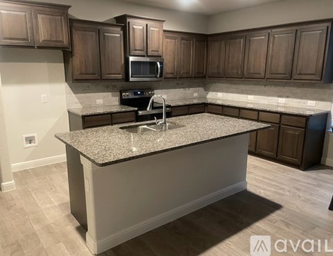 A kitchen with a granite countertop and wooden cabinets.