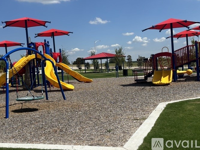 A playground with a yellow slide and red umbrellas.