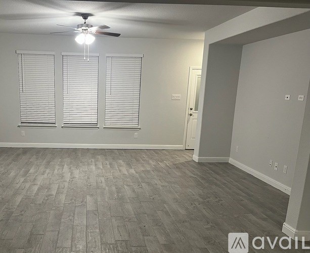 A room with a ceiling fan and wooden flooring.