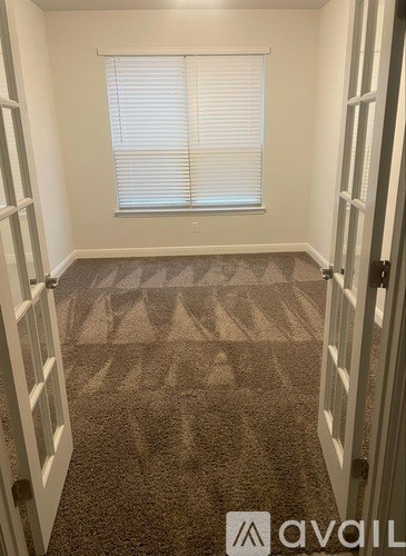 A carpeted room with a window and a door.