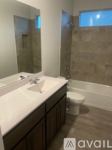 A bathroom with a toilet, sink, and tiled shower.