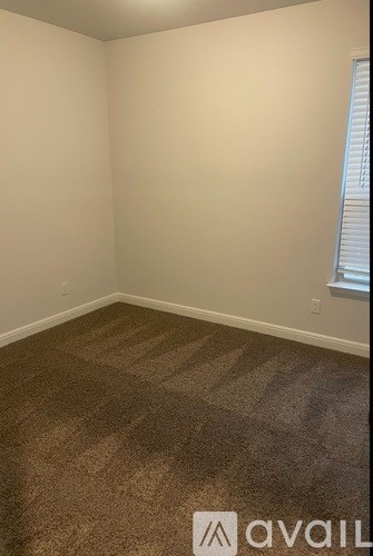 A room with a carpeted floor and a window with blinds.